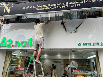 Thợ kỹ thuật đang lắp đặt biển quảng cáo tại tiệm A2 Nail